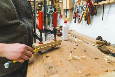 Carpenter during work. Woodworking expert glueing two wood pieces together with Stock Photos