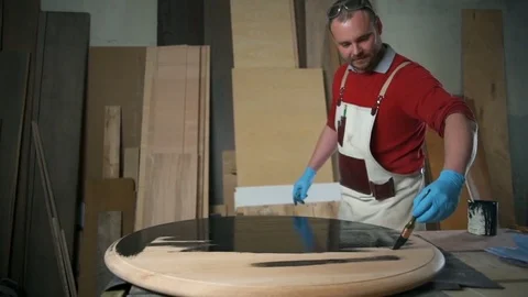 Carpenter dyeing the table with black paint in the workshop slow motion Video stock 74497116