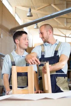 Carpenter examining work of a trainee Stock Photos
