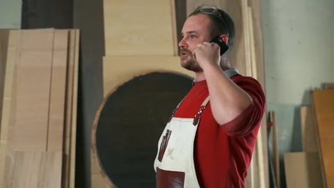 Carpenter explaining something and talking on the phone in workshop slow motion Stock Footage 74508773