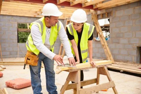 Carpenter With Female Apprentice Working On Building Site Stock Photos