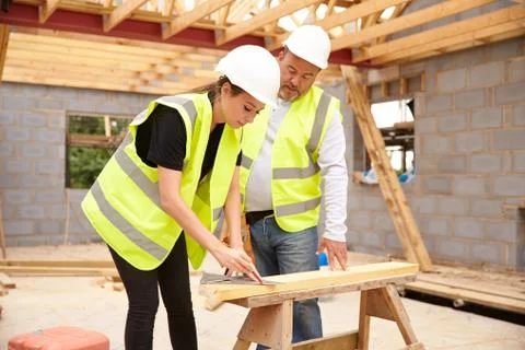 Carpenter With Female Apprentice Working On Building Site Stock Photos
