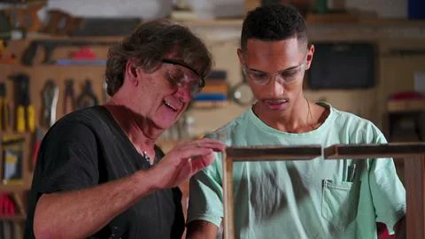 Carpenter Guiding Apprentice at Carpentry Workshop, Teaching Woodwork Using.. Stock Photos