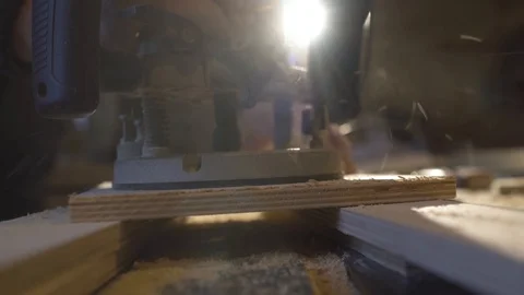 The carpenter with a hand-held mill cuts out a circle from a wooden shield Stock Footage 107614557