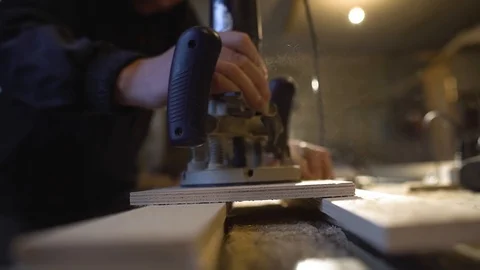 The carpenter with a hand-held mill cuts out a circle from a wooden shield Video stock 107614635