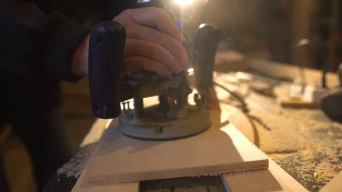 The carpenter with a hand-held mill cuts out a circle from a wooden shield Stock Footage 107614752