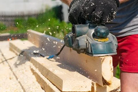 Carpenter hands plan lumber with an electric plane Stock Photos
