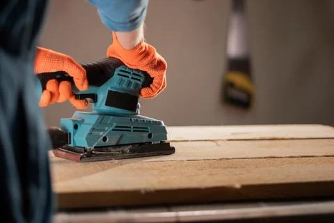 Carpenter hands with sander at workshop for polish. wood worker using elect.. Stock Photos