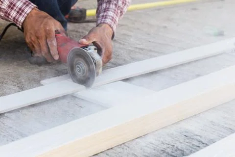Carpenter hands using electric saw on wood at construction site Stock Photos