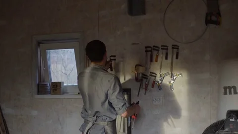 Carpenter hanging up tools on the wall after work day Stock Footage 76108903