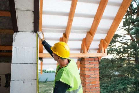 Carpenter in helmet marks line for future rafter on concrete wall, initial .. Stock Photos