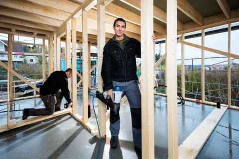Carpenter Holding Drill While Colleague Working At Construction Foto stock