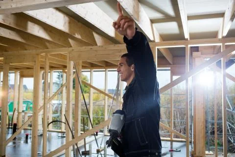 Carpenter Holding Drill While Pointing At Construction Site 写真素材