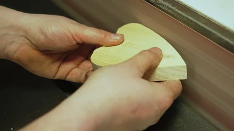 Carpenter holding a tiny heart shaped wooden piece near the grinding machine Stock Footage 241042277