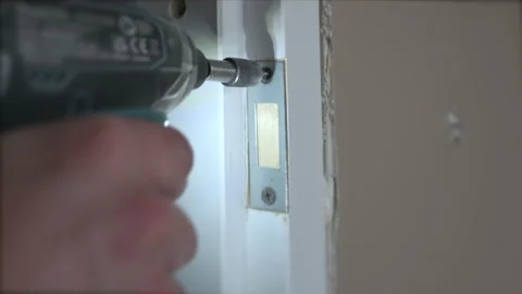 The carpenter installation the lock into the door with a drill Stock Footage 178465855