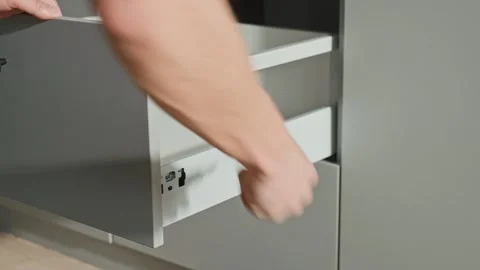 Carpenter installing and adjusting drawer front in modern kitchen cabinet Stock Footage 306577852