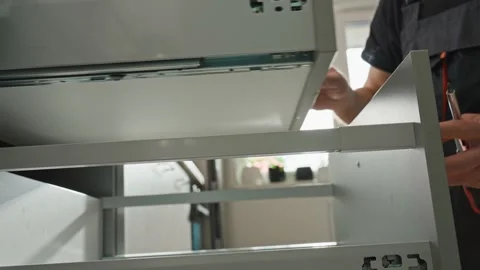 Carpenter installing and adjusting drawer front in modern kitchen cabinet Stock Footage 306578005