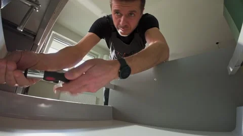Carpenter installing and adjusting drawer front in modern kitchen cabinet Stock Footage 306578762