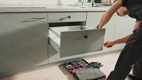 Carpenter installing and adjusting drawer front in modern kitchen cabinet Stock Footage 307830140