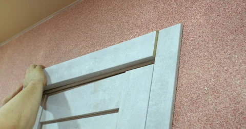 Carpenter installing door frame molding on a white door Stock Footage 305662256