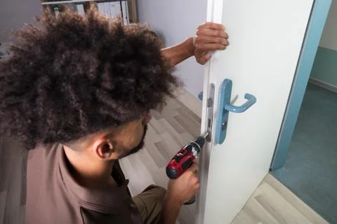 Carpenter Installing Door Lock With Wireless Screwdriver Stock Photos