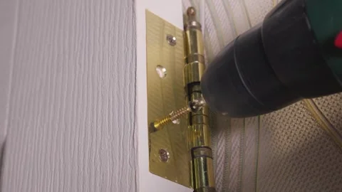 Carpenter installing golden hinge on white door with electric screwdriver 스톡 동영상 304118054