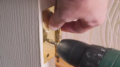 Carpenter installing golden hinge on white door with electric screwdriver Stock-Footage 304118069