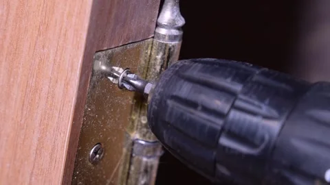 Carpenter installing golden hinge on wooden door with cordless drill Vidéo 304119787