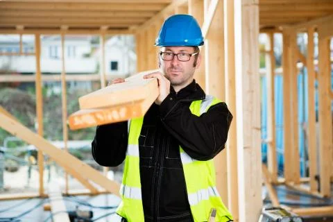 Carpenter Looking Away While Carrying Wood On Shoulder Stockfoto's