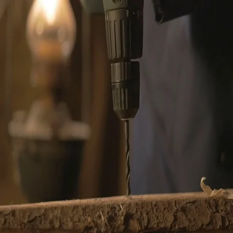 The carpenter makes a hole in the Board drill. master works in the Studio tool Video stock 69518966