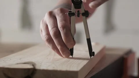 A carpenter marks a pine wooden plank with a compass. woodworker Stock Footage 156670369