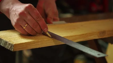 The carpenter measures and marks the wood in the workshop to cut Stock Footage 193743854