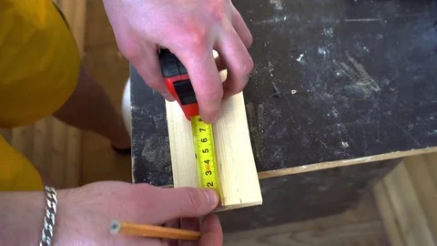 The carpenter measures and saws off a piece of Board Stock Footage 74751267