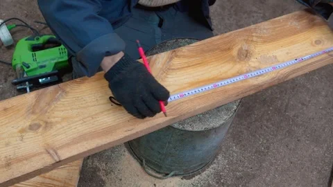 Carpenter measuring and marking wood plank for cutting Видео 333696161