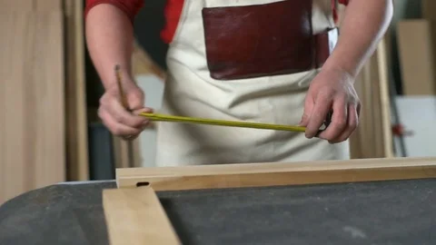 Carpenter measuring a plank and making marks with pencil in workshop closeup Stock Footage 74506909