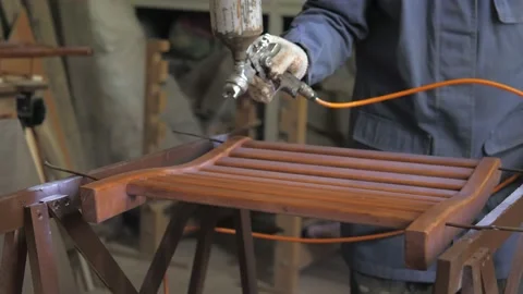 Carpenter-men wearing gloves, apply varnish or primer with compressed air on a Stock Footage 201301150