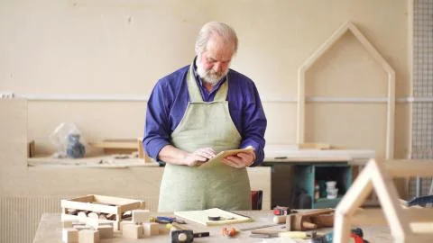 Carpenter or carpenter works in a workshop, making a sketch of a birdhouse, a Stock Photos
