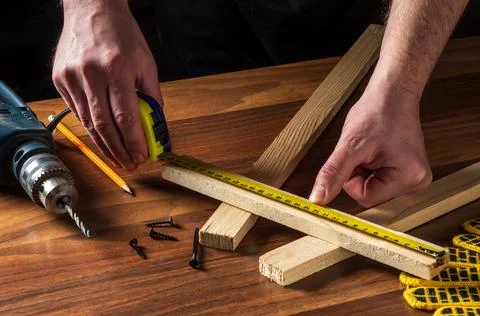 Carpenter or woodworker uses a construction tape to measure the length Stock Photos