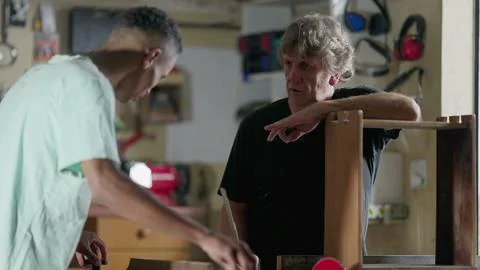 Carpenter orienting apprentice at woodworking carpentry workshop . Candid t.. Foto stock