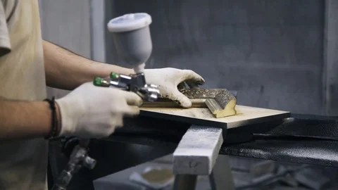 Carpenter is painting a sample of frame for canvas using gold paint. Stock Footage 72256542