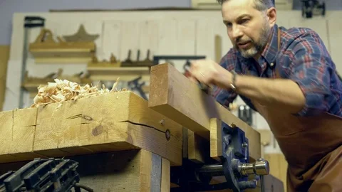 Carpenter Planes Solid Wood in his Workshop Stock Footage 84909819