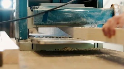 A carpenter planes a workpiece with a woodworking machine.  Stock-Footage 143387833