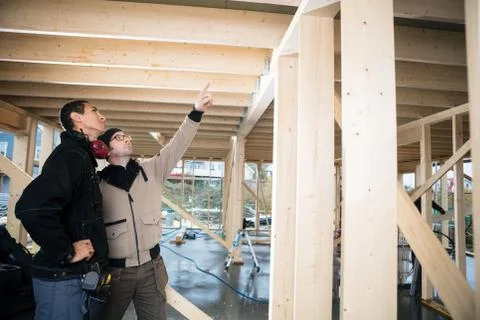 Carpenter Pointing On Wood While Standing By Colleague Stock Photos