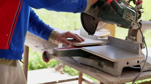 Carpenter positioning wood boards under bench mounted miter saw in outdoor Stock Footage 344874207