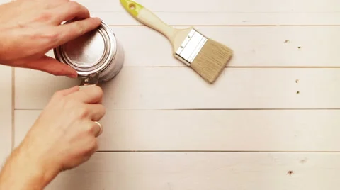 A carpenter prepares his working place: opens up a tin with blue paint Stock-Footage 57323453