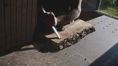 A carpenter processes a wood board with a chisel. Artisan makes a beautiful Stock Footage 205943744