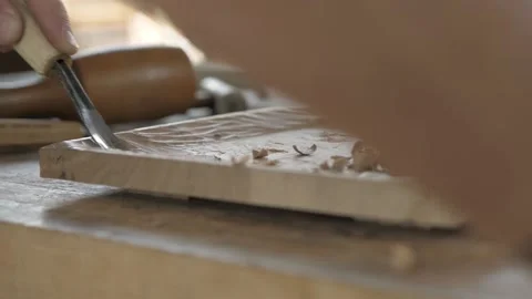 A carpenter processes a wooden board with a chisel and mallet. craftman makin Stock Footage 137149692