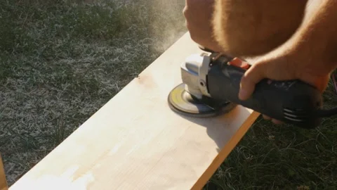 A carpenter is processing wood with a grinder. A worker grinds and polishes a Video stock 195005157