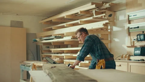 Carpenter in Protective Glasses Using Chainsaw While Working With Wooden Plate Video stock 236473624