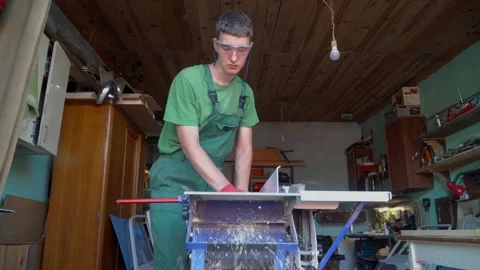 Carpenter in protective gloves and glases handles a wooden board works on planin Stock Footage 167613441